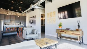 Een moderne woonruimte met een bank, salontafel en een eethoek met stoelen.