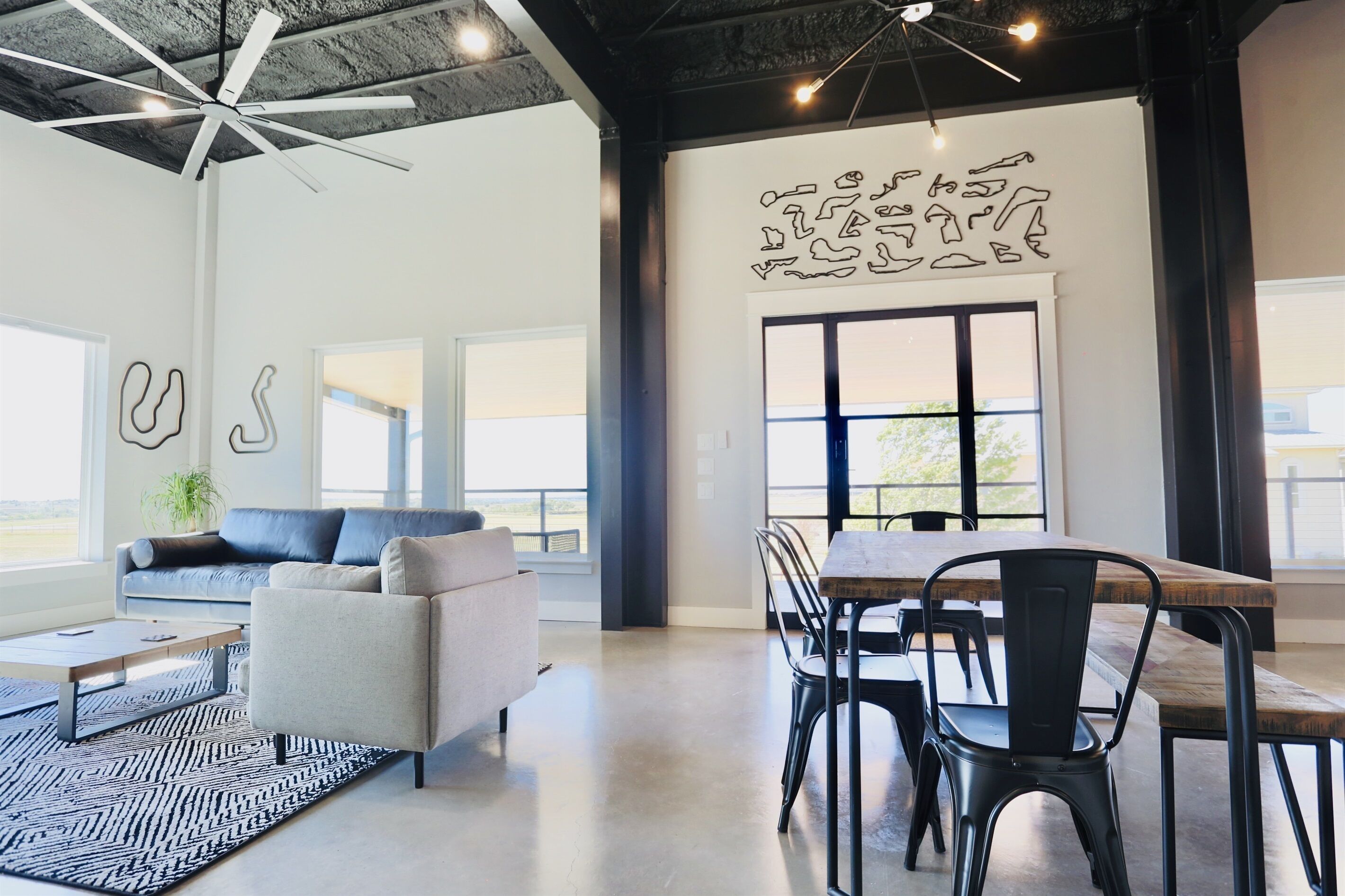 A modern interior with a sofa, dining table, chairs, and abstract wall art.