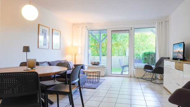 Un salon moderne comprenant une table à manger, des chaises, un canapé et un téléviseur.
