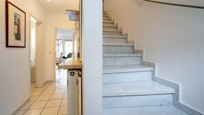 Un couloir avec un escalier en marbre menant à un deuxième étage.