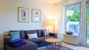 Un salon avec un canapé, une table basse ronde, une lampe et deux tableaux encadrés accrochés au mur.