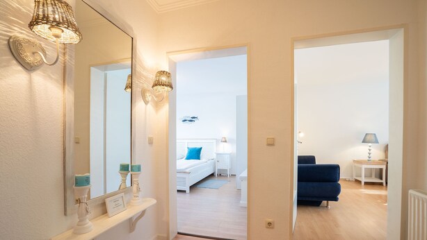 Quarto moderno com uma cama grande, mesas de cabeceira e um sofá azul.