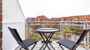 A balcony with two black wicker chairs and a small round table. - Vacation apartment "Musick-Jischa" for up to 2 persons (non-smokers) (Niendorf/Ostsee)