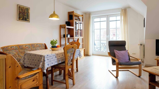 A cozy living room with a sofa, a dining table, a rocking chair, and a bookshelf. - Vacation apartment "Musick-Jischa" for up to 2 persons (non-smokers) (Niendorf/Ostsee)