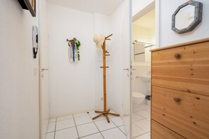 A bathroom with a wooden floor, a wooden vanity, a mirror, and a towel rack.