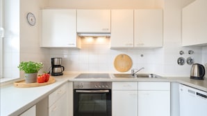 Een moderne keuken met witte kastjes, een roestvrijstalen oven, een vaatwasser en een koffiezetapparaat.