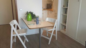 Un comedor con mesa, sillas y una cocina al fondo.