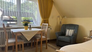 Una habitación acogedora con una cama, una mesa de comedor con sillas, una silla y un radiador.
