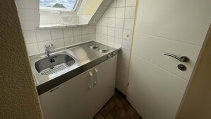 Una cocina compacta con ventana, un fregadero y una estufa.
