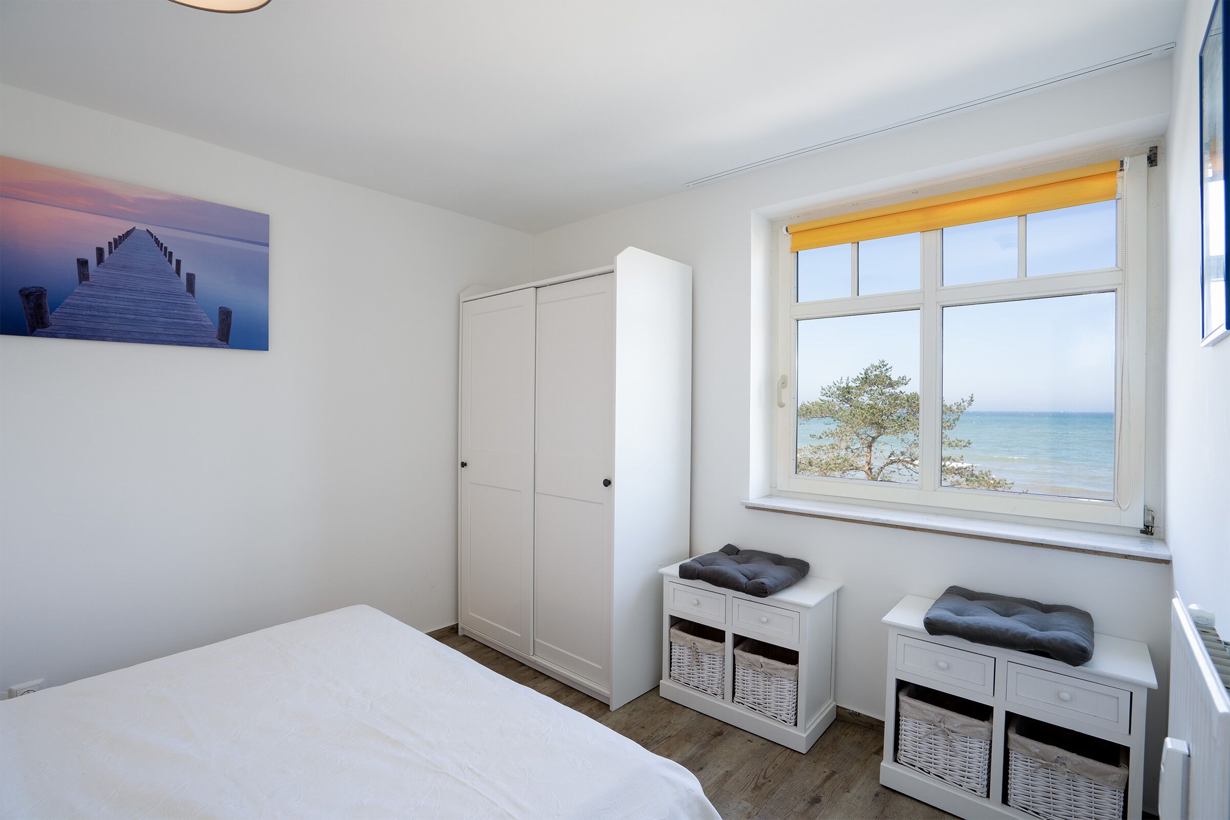 Een slaapkamer met een bed, een kledingkast, een raam met uitzicht en een schilderij aan de muur.