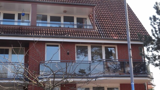 Ein zweistöckiges Gebäude mit Ziegeldach, einem Balkon im Obergeschoss und einer Ziegel-Fassade.
