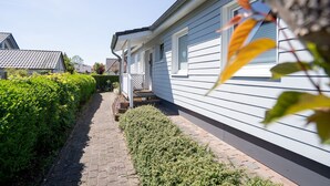 A row of white houses with a paved walkway and neatly trimmed hedges.