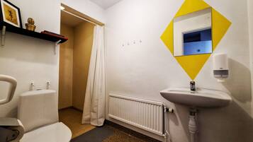 A bathroom with a toilet, sink, shower, and a radiator.