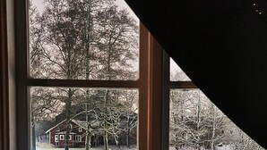 Janela com vista para uma paisagem nevada, um vaso de planta e um suporte de metal.