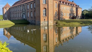 A large brick building with multiple windows and a pond in front. - Parkhuset  (Hadsund)
