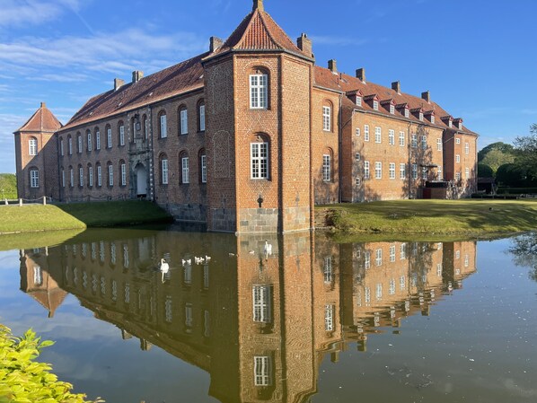 Un grand bâtiment en briques, doté de nombreuses fenêtres et bordé d’un étang.