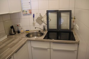 Kitchen features a stainless steel sink, electric stove, and double oven, along with white cabinetry and a light-colored countertop.