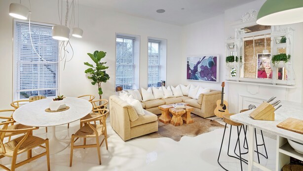 Ein modernes Wohnzimmer mit einem runden Esstisch, einem beigen Sofa und einer Gitarre.