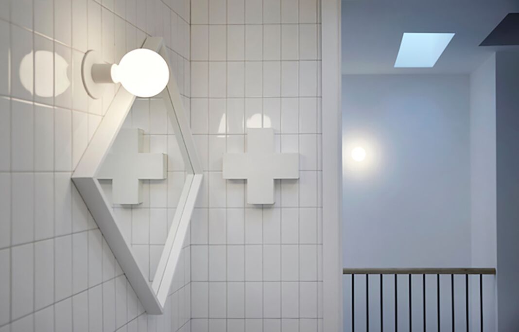 Un intérieur moderne avec un motif géométrique sur un mur, un escalier et une lucarne.