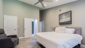 A bedroom with a bed, a gray armchair, and a ceiling fan. - Modern Villa Retreat in Saddlebrook Resort (Zephyrhills)