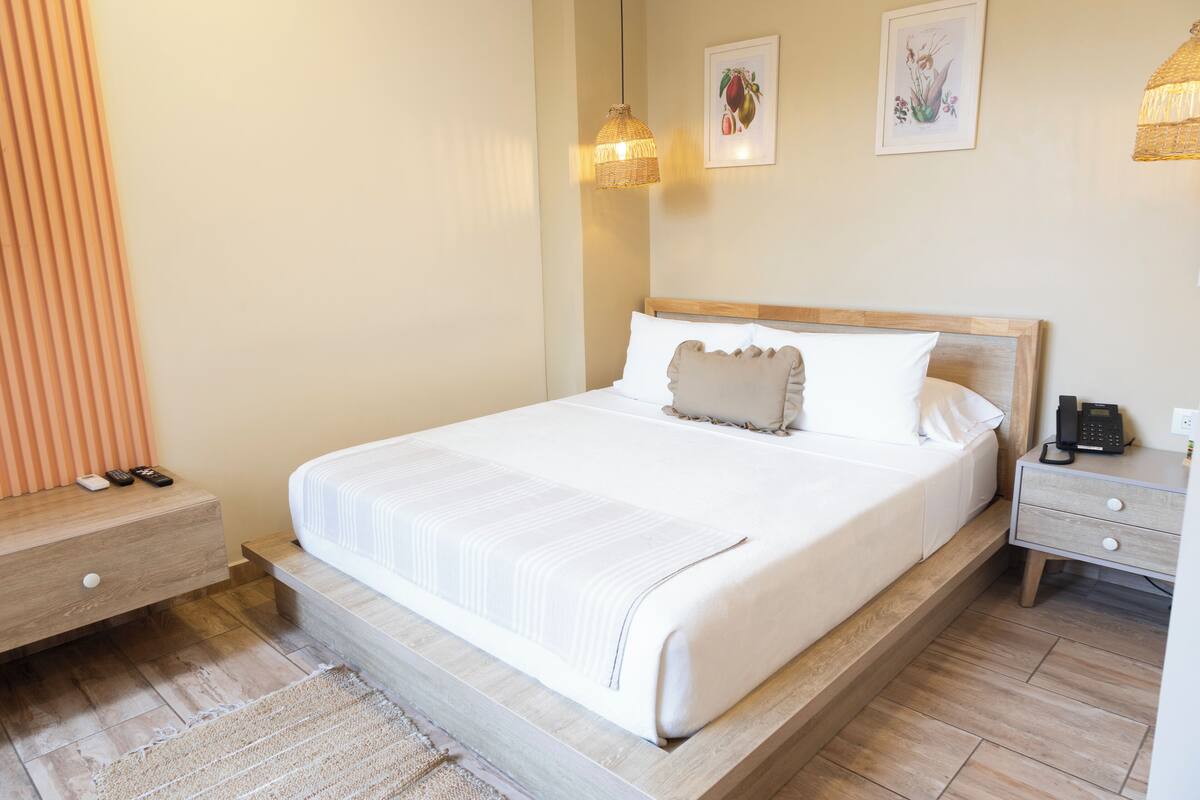 Une chambre à coucher bien rangée, avec un grand lit, des tables de chevet et une lampe de chevet.