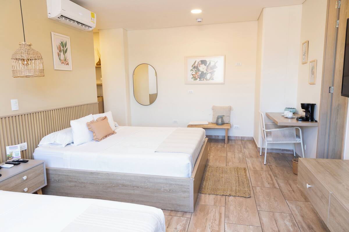 Une chambre d’hôtel avec un grand lit, des tables de chevet, un bureau, une chaise et un téléviseur.