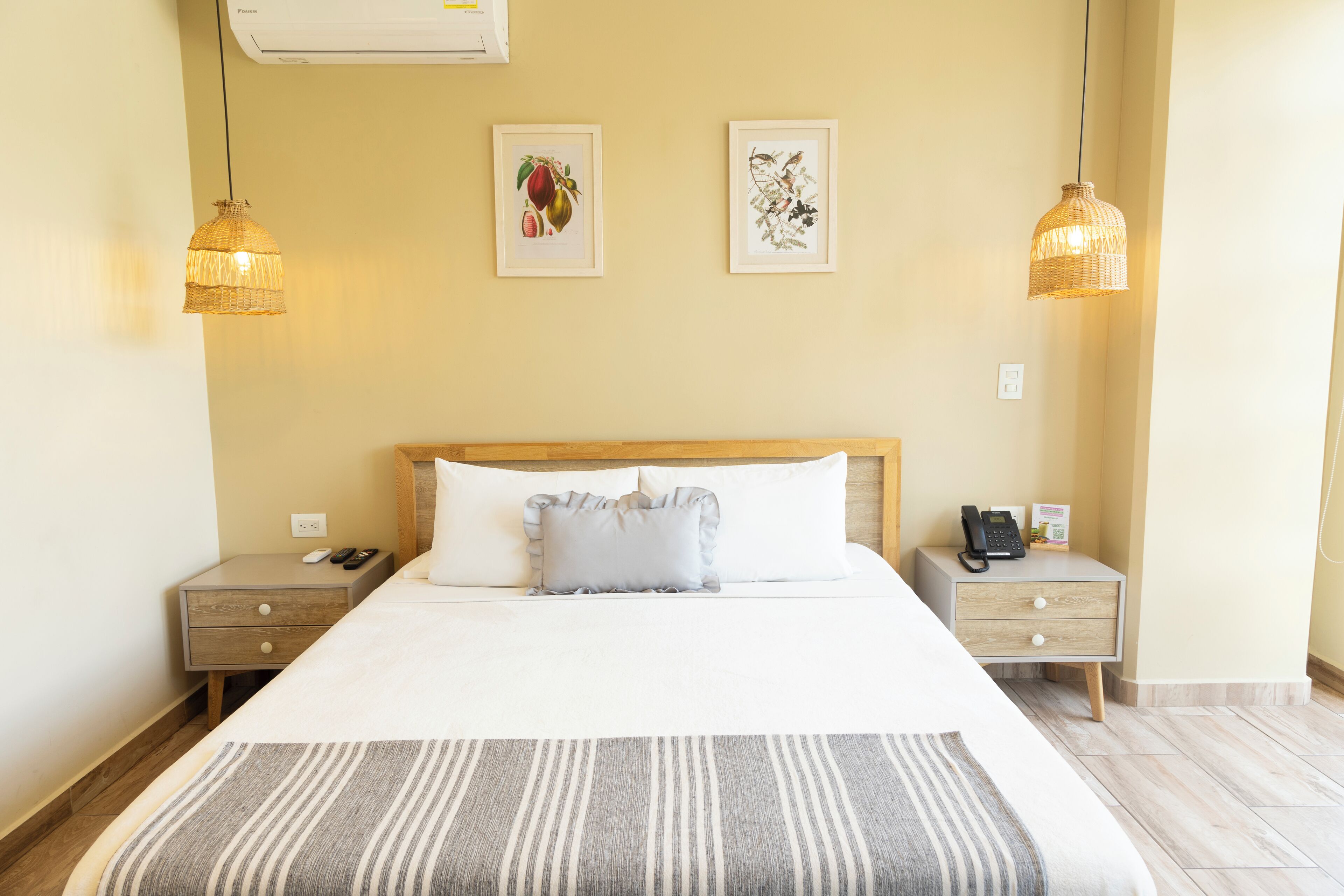 A hotel room with a large bed, two bedside tables, a telephone, and two wall-mounted light fixtures.