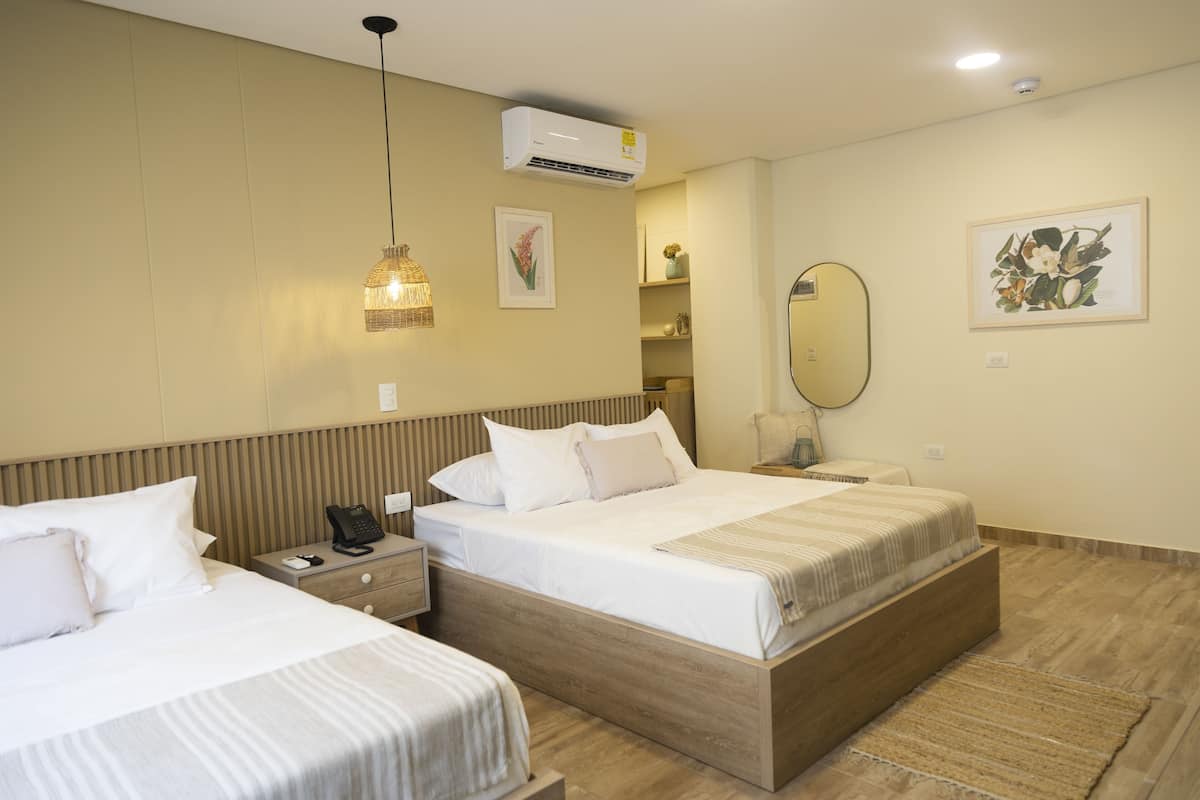 Une chambre d’hôtel avec deux lits, une table de chevet avec un téléphone, un miroir et des œuvres d’art accrochées au mur.