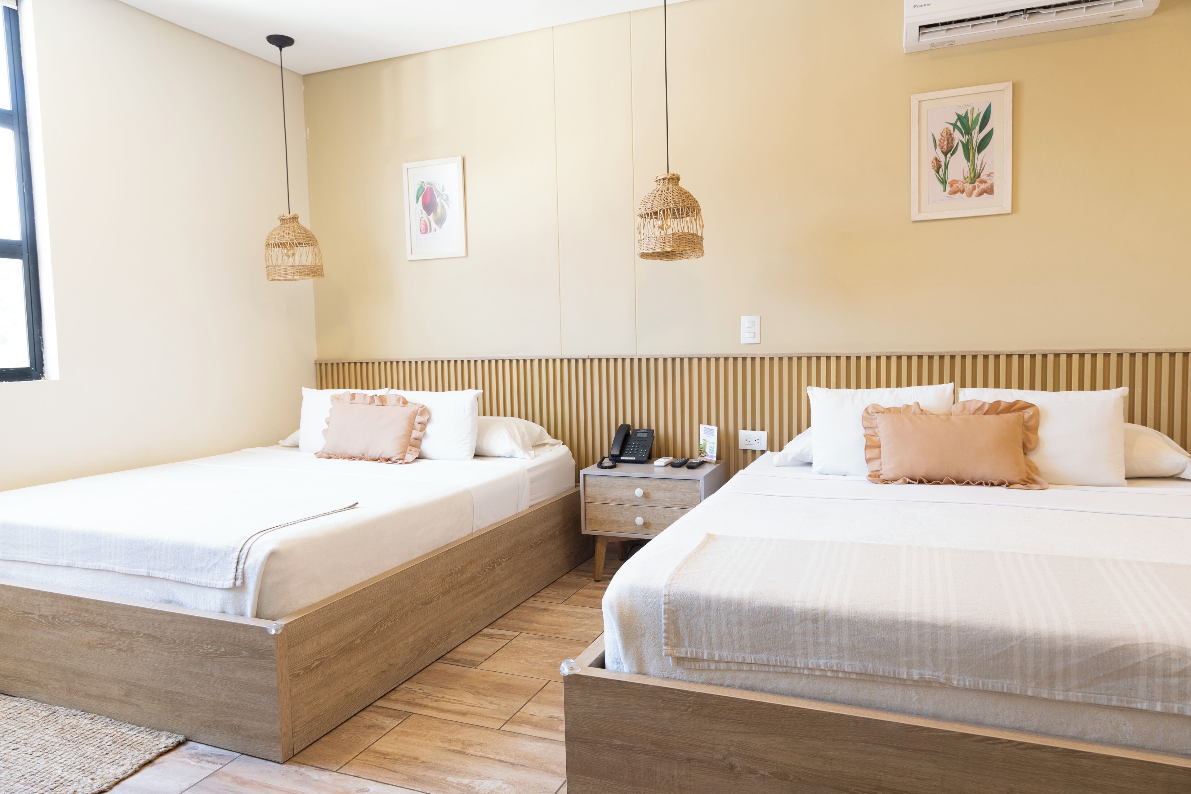 Ein Hotelzimmer mit zwei Betten, einem Nachttisch und einem an der Wand befestigten Telefon.
