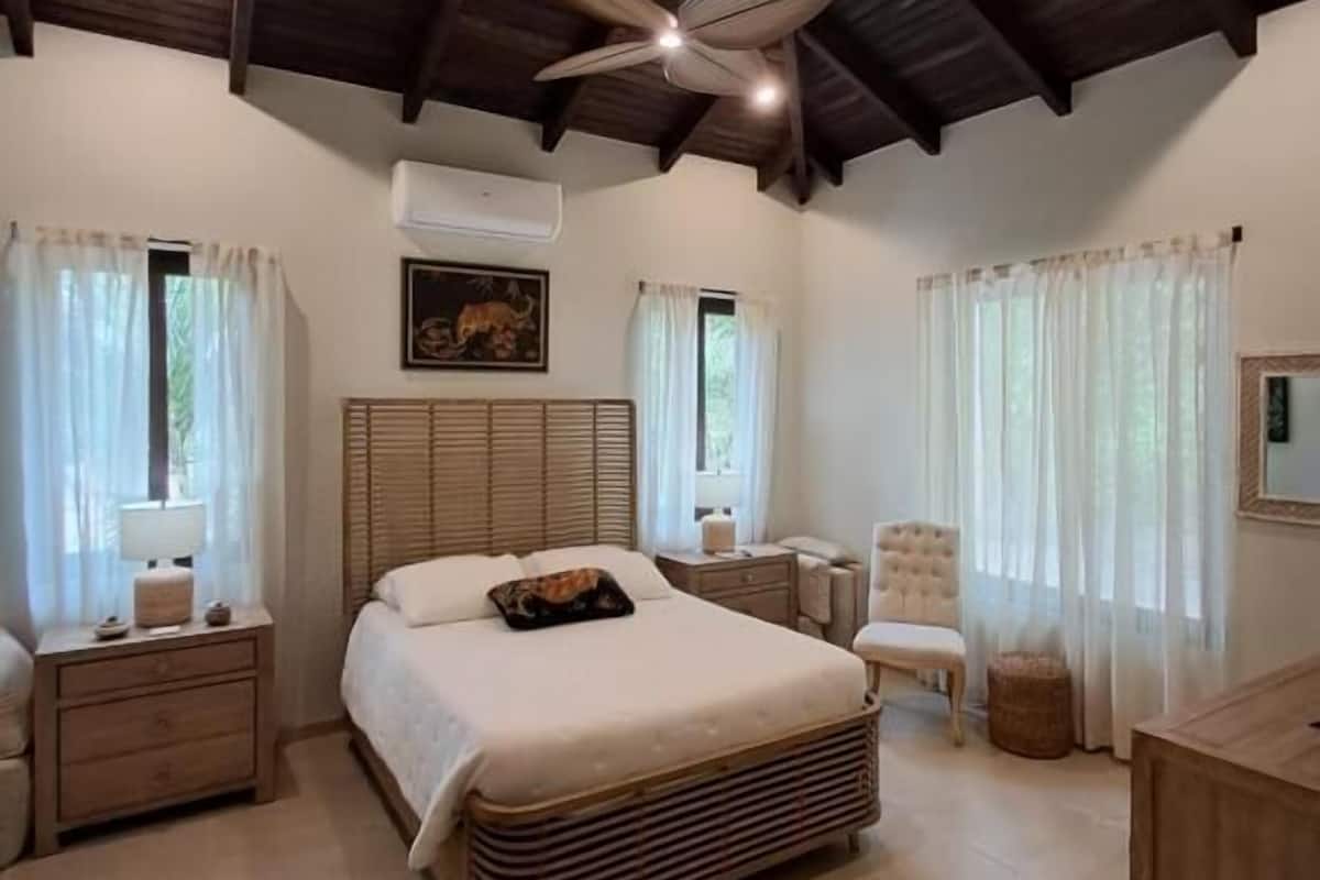 A spacious bedroom with a large bed, a wooden ceiling, and a ceiling fan.