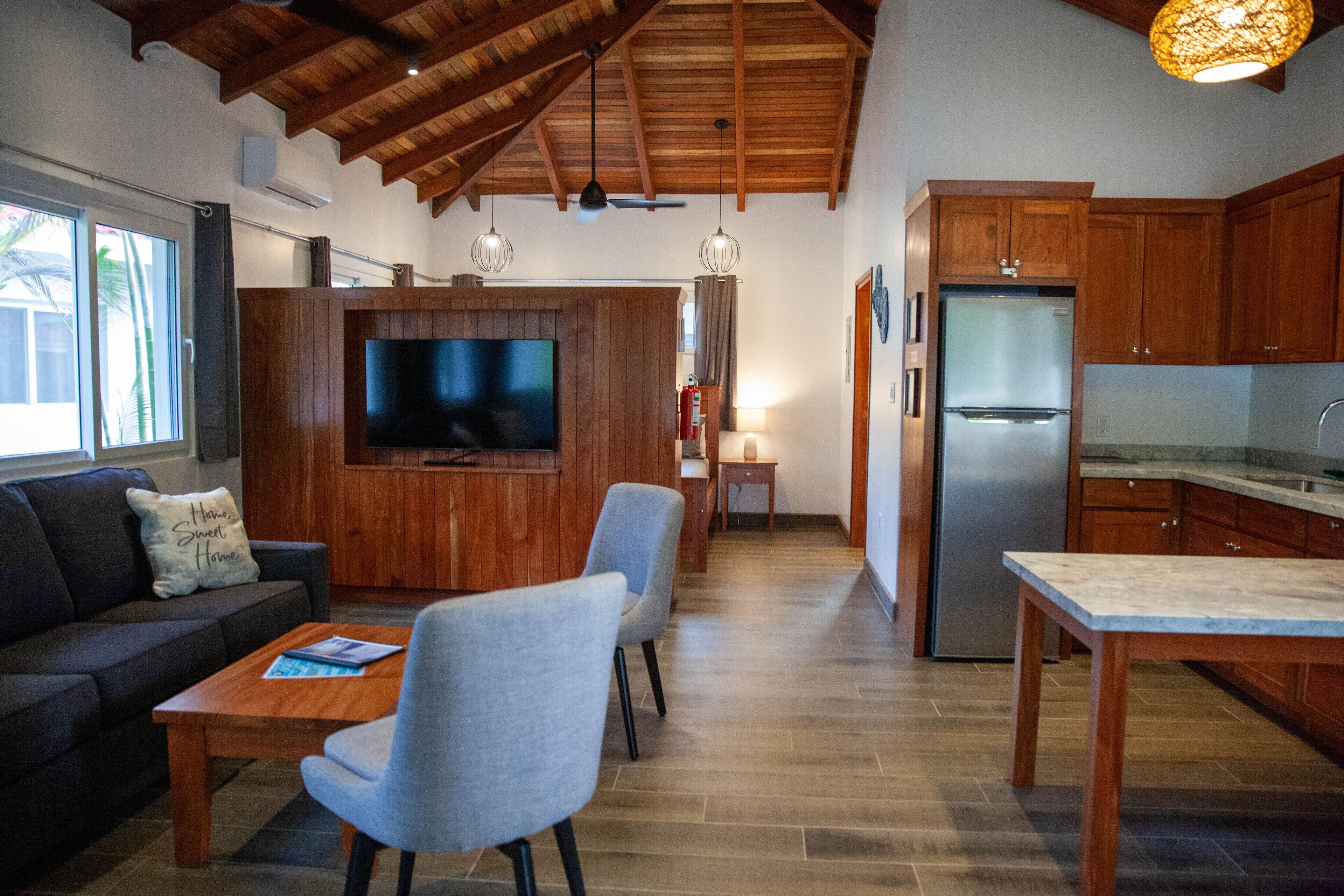 A modern kitchen with wooden cabinets, a built-in refrigerator, and a dining area with a table and chairs.