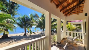 A covered outdoor area with a view of the beach and palm trees. - Ceiba Beach Resort (Placencia)
