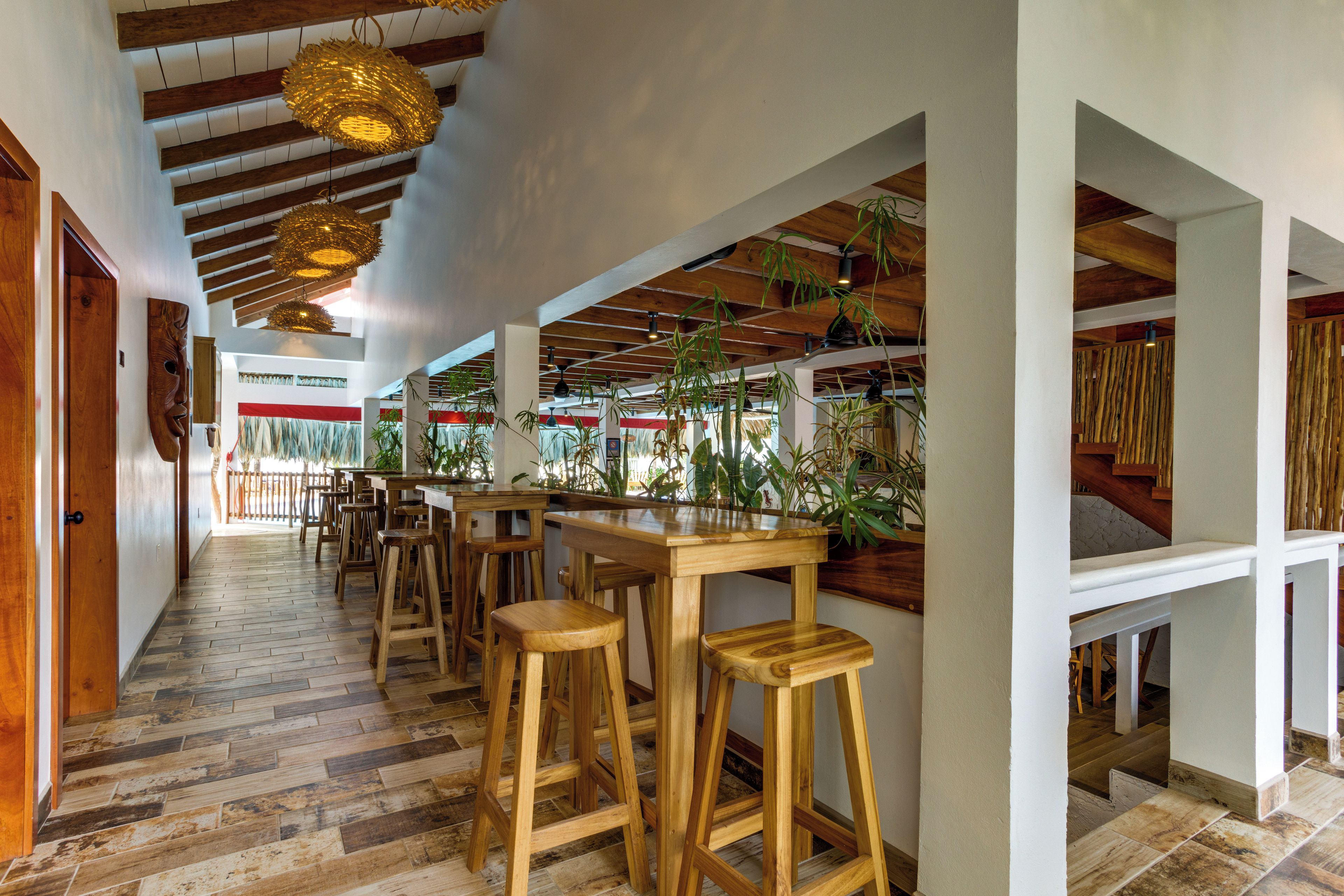A restaurant interior with wooden floors, high ceilings, and hanging light fixtures.
