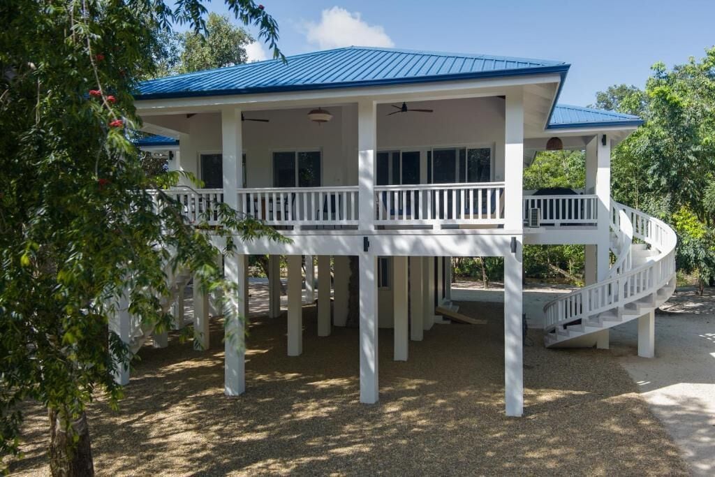 A two-story house with a blue roof, white exterior, and a covered porch with a white railing.