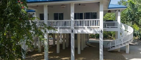 A two-story house with a blue roof, white exterior, and a covered porch with a white railing.