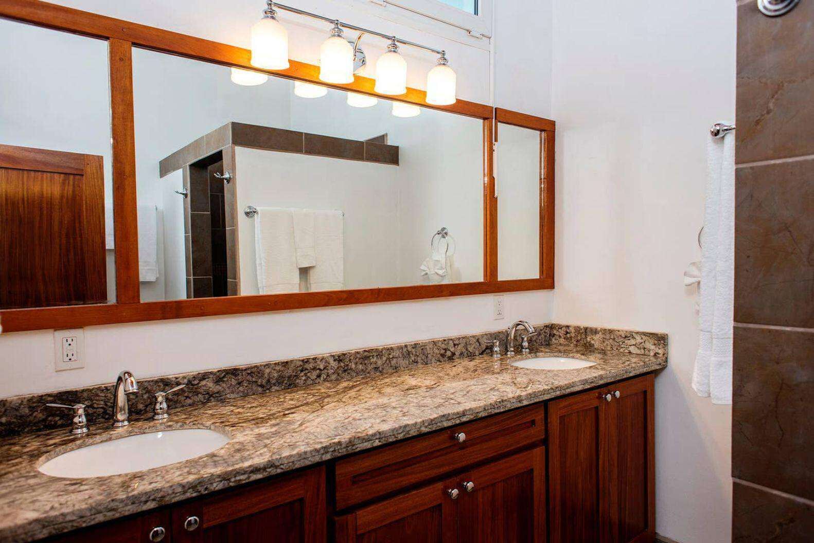 Un baño con dos lavamanos, un espejo grande y una zona de ducha.