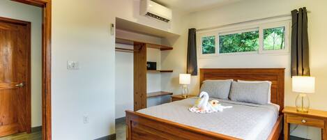A bedroom with a wooden bed, a ceiling fan, a window with a view of trees, and a built-in shelf.