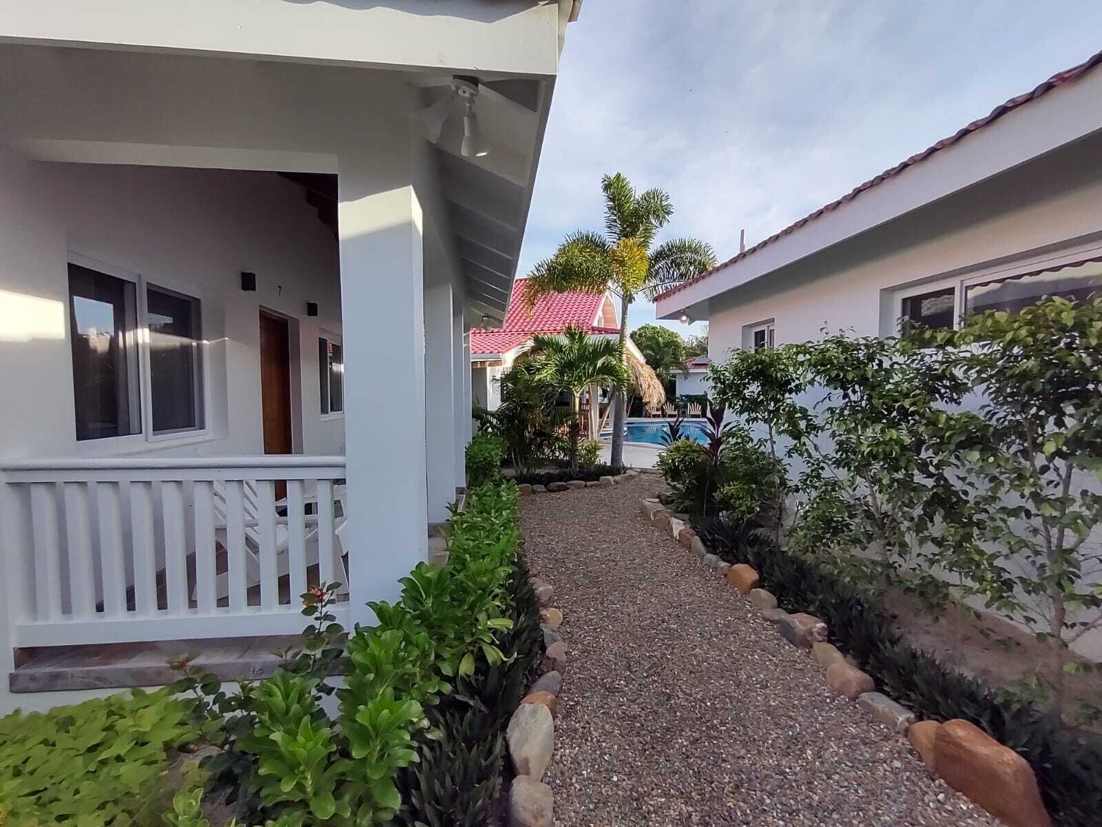 Un chemin menant à un bâtiment à l’extérieur blanc et au toit recouvert de tuiles rouges.