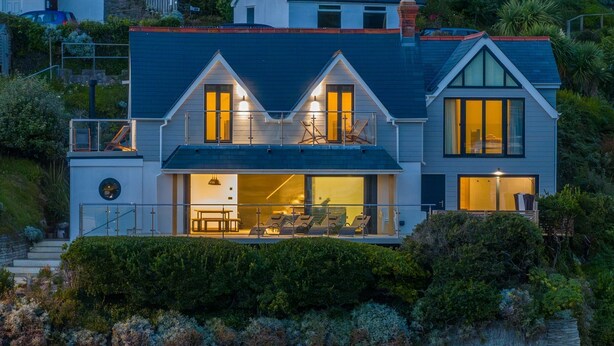 Een modern huis met twee verdiepingen, een balkon, een eethoek en een groot raam met uitzicht op de tuin.