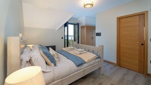 Een slaapkamer met een bed, een houten kledingkast en uitzicht op de omgeving.