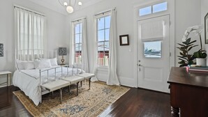 A bedroom with a large bed, a bench, a rug, and a view of the outside. - Uptown Designer Home l 3 bedroom l 3 blocks to Magazine St (New Orleans)