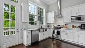 A spacious kitchen with white cabinets, a stainless steel range, a microwave, and a dishwasher. - Uptown Designer Home l 3 bedroom l 3 blocks to Magazine St (New Orleans)