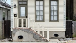 A two-story house with a balcony, a front door, and a staircase leading to the entrance. - Uptown Designer Home l 3 bedroom l 3 blocks to Magazine St (New Orleans)