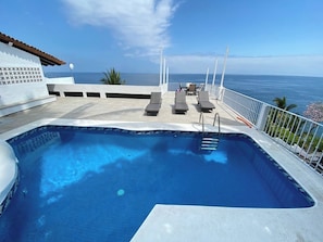 A swimming pool with lounge chairs and a view of the ocean.