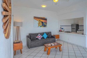 Un salon avec un canapé gris, une table basse en bois et un tableau coloré accroché au mur.
