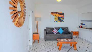 A living room with a grey sofa, a wooden coffee table, a floor lamp, and a painting on the wall.