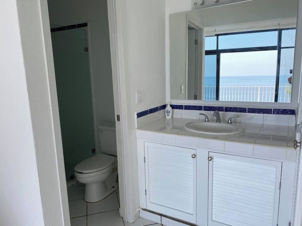 A bathroom with a toilet, a sink, and a mirror.