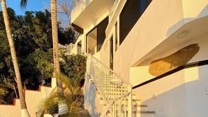 A modern building with a white exterior, a staircase with white railings, and palm trees in the background. - Oceanfront Condo w/Pool & Balcony Views (Aguacate)