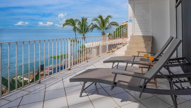 A balcony with a view of the sea, equipped with lounge chairs and a table. - Oceanfront Condo w/Pool & Balcony Views (Aguacate)