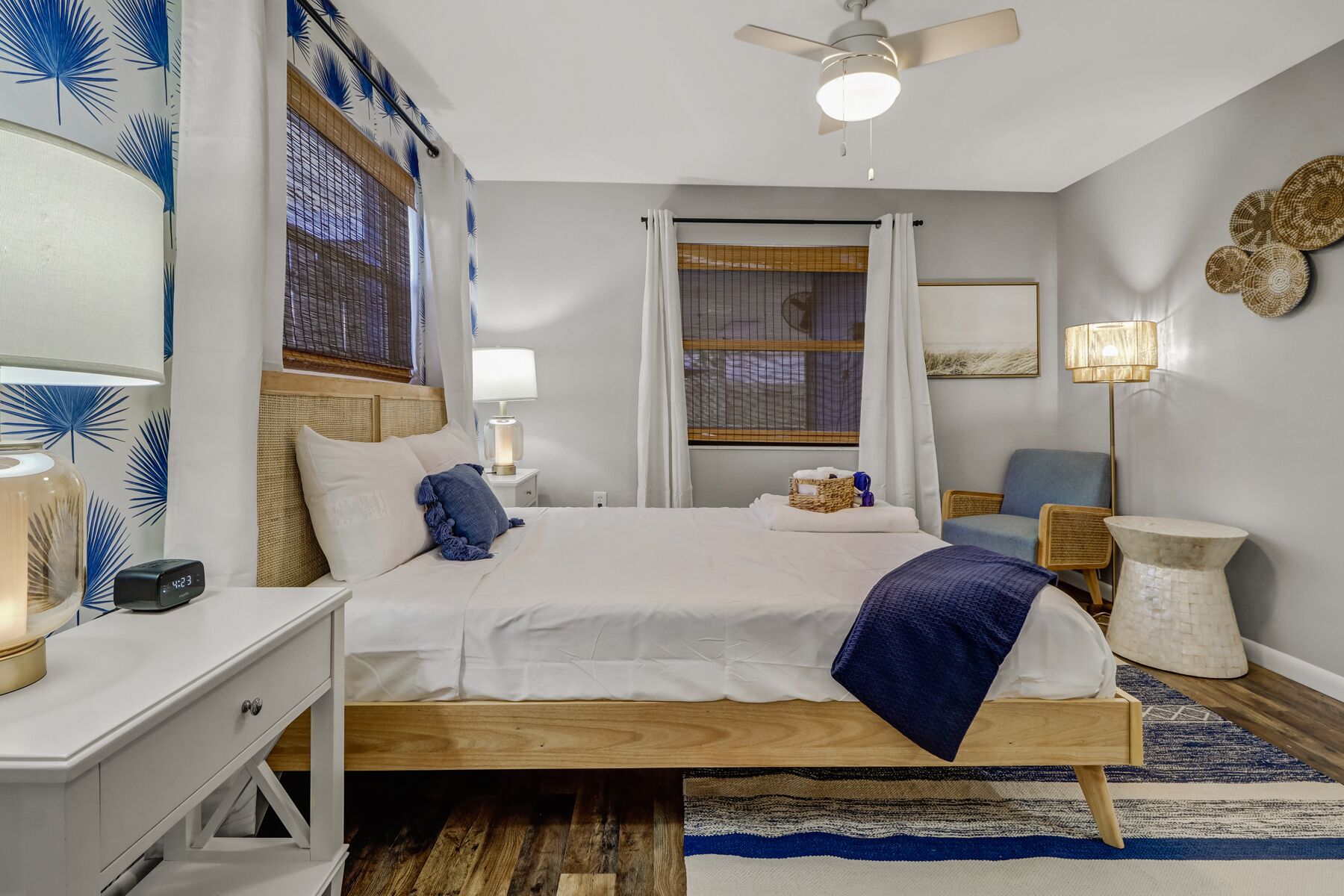 A modern bedroom with a wooden bed, white bedding, a nightstand with a lamp, a chair, and a small table.